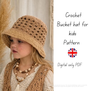 以下が含まれることがあります： 子供用のベージュ色のクロシェバケットハット。つばが広く、模様が入っています。画像には「Crochet Bucket hat for kids Pattern Digital only PDF」というテキストも含まれています。