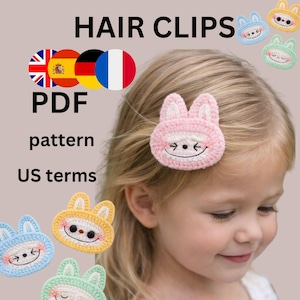 Puede incluir: Una niña rubia lleva una pinza para el pelo de crochet con forma de conejito rosa. La imagen muestra el texto "CUTE CROCHET HAIR CLIPS" y "PDF pattern US terms". Se ven más pinzas para el pelo de conejito de crochet.