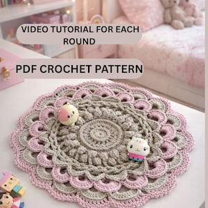 Può includere: Un centrino all'uncinetto nei toni del grigio e del rosa, con un design circolare. Il testo "INSTANT DOWNLOAD ADJUSTABLE SIZE", "VIDEO TUTORIAL FOR EACH ROUND" e "PDF CROCHET PATTERN" sono visibili. Due piccoli giocattoli sono sul centrino.