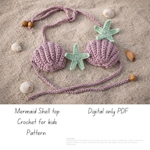 May include: A crochet mermaid shell top in a light purple color, with two shell-shaped cups and green starfish accents. The top is displayed on a sandy surface with seashells. The text on the image says "Mermaid Shell top Crochet for kids Pattern".