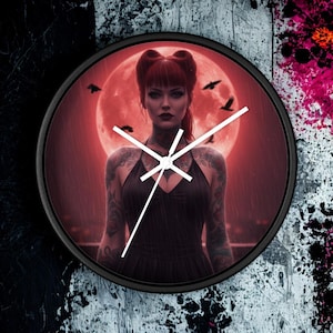 May include: Black round wall clock with a black frame. The clock face features a woman with tattoos in front of a red moon, with black birds flying. The clock hands are white.