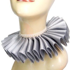 May include: A silver ruffled collar with a white lace trim. The collar is made of satin and has a pleated design.