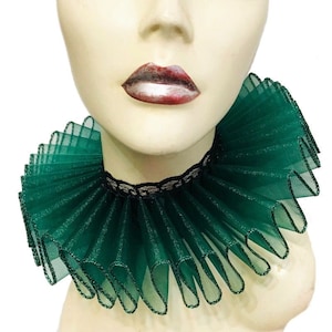 May include: A green ruffled collar made of sheer fabric with a black lace trim. The collar is worn on a mannequin's neck.