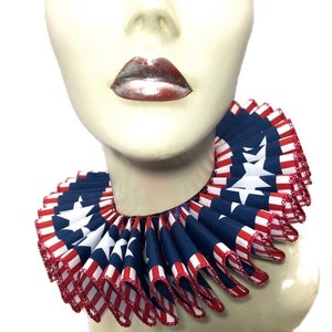 May include: A red, white, and blue ruffled collar with stars and stripes. The collar is made of fabric and has a sewn edge.