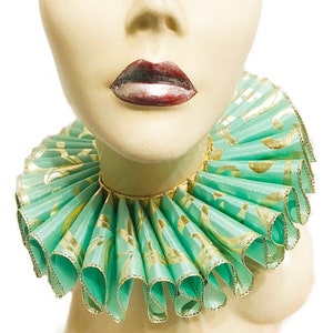 May include: A green and gold ruffled collar with a gold trim. The collar is made of a soft, silky fabric and has a delicate, feminine look.