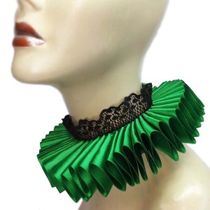 May include: A green satin ruffle collar with a black lace trim. The collar is worn on a mannequin's neck.