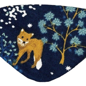 May include: A navy blue eye patch with a golden fox, trees, and white details. It has a black elastic strap. The eye patch is decorated with a forest scene.