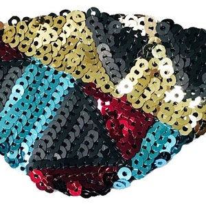 Pode incluir: Um tapa-olho colorido feito de lantejoulas em tons de dourado, preto, azul-turquesa e vermelho. O tapa-olho é desenhado em um padrão geométrico e tem uma faixa elástica para um ajuste seguro.