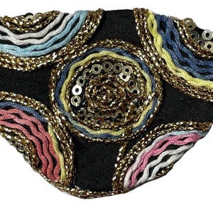 May include: Black eye mask with colorful embroidered circular designs. The mask features gold, pink, blue, and yellow thread, along with gold sequins. The design is set against a black fabric background.