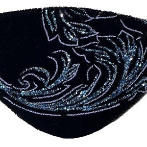 May include: A black eye patch featuring a shimmering blue glitter floral pattern across the surface. The eye patch is constructed from a soft fabric material and includes a thin black elastic strap attached to both sides for secure placement.