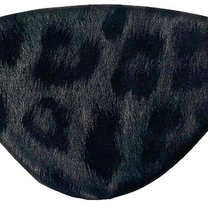 May include: A black eye patch with a leopard print design. The eye patch is made of a textured material and has a black elastic band attached. The eye patch is designed to cover one eye.
