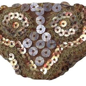 Può includere: Una benda sull'occhio decorativa con una base in tessuto marrone, impreziosita da paillettes scintillanti in tonalità oro e argento. Le paillettes sono disposte in un motivo a spirale. È attaccato un elastico nero.