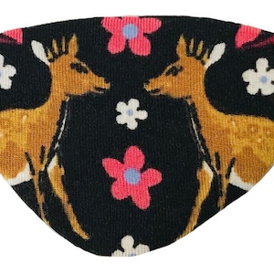 Puede incluir: Una máscara para dormir negra con un patrón repetido de ciervos estilizados y flores rosas y blancas.