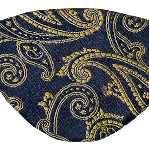Puede incluir: Un parche para el ojo azul oscuro con un patrón de paisley dorado.