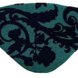May include: A green eye patch with a black floral pattern. The patch is made of fabric and has a gold elastic band.