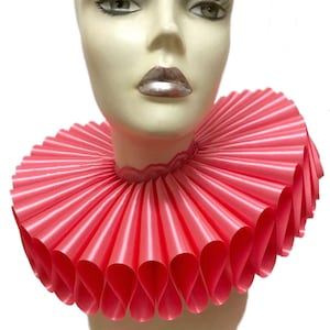 May include: A pink ruffled collar made of satin ribbon. The collar is large and dramatic, and would be perfect for a costume or a theatrical performance.