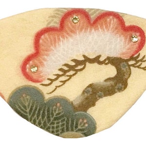 May include: A cream-colored eye mask with a Japanese-inspired design featuring a stylized tree with red and white blossoms and green leaves. The mask has three small, clear rhinestones.
