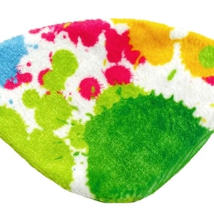 May include: A white eye mask with a colorful paint splatter design. The mask is made of soft, plush fabric and has adjustable straps.