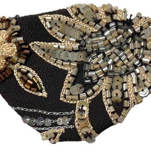 May include: A black eye patch with gold and silver sequins and beads in a floral design.