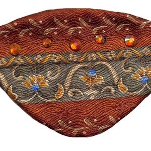 Può includere: Un paraluce marrone e dorato con strass. Il paraluce ha un elastico nero.