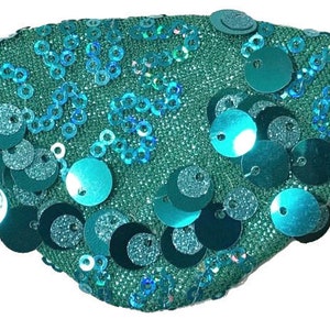 May include: A turquoise eye patch with sequins in a circular pattern. The sequins are iridescent and have a light blue and green color.