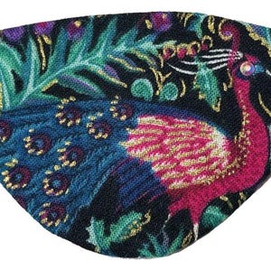 Puede incluir: Un parche decorativo para el ojo con un diseño de pavo real. El parche tiene un fondo negro con un pavo real colorido en tonos de azul, rosa y dorado. El diseño incluye follaje verde y detalles dorados. Se adjunta una banda elástica.