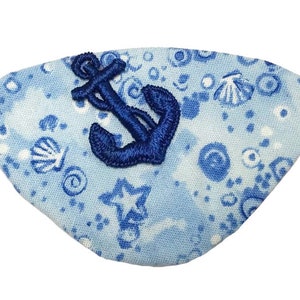 May include: A blue eye patch with a white background and a blue anchor design. The background has a pattern of white seashells, stars, and circles.