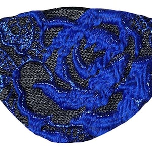 May include: An eye patch featuring a black mesh base with an intricate, raised blue floral embroidery pattern. The design includes a shimmering texture within the blue thread work and thin black elastic straps extending from the sides of the patch.
