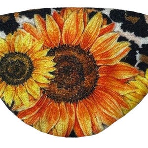 以下が含まれることがあります： 黒と茶色のヒョウ柄の生地に、黄色とオレンジ色の大きなひまわりが2つ描かれています。ひまわりの中心は濃い茶色です。