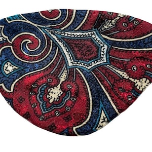 Könnte beinhalten: Eine Augenmaske mit Paisley-Muster in Rot, Blau und Weiß mit schwarzen Gummibändern.