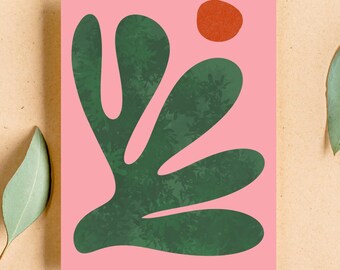 May include: A rectangular art print featuring a solid pink background with a large, organic, dark green shape that resembles a stylized leaf or coral. Above the green form, there is a small, solid, burnt orange circle positioned in the upper right.