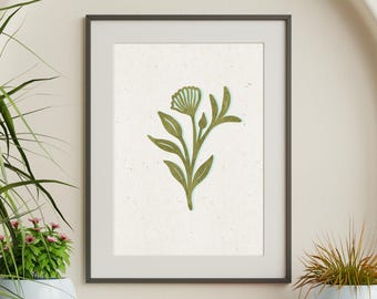 May include: A framed wall art print featuring a centered olive green botanical illustration of a single flower with leaves on a textured off-white background. The artwork is enclosed in a thin black frame, showcasing a clean and simple design.