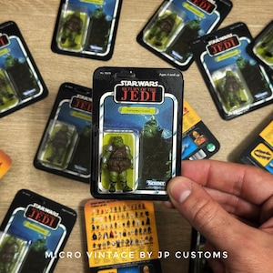 Op de afbeelding: Een verzameling vintage Star Wars actiefiguurkaarten met Gamorrean Guard-figuren. De kaarten zijn zwart met het Star Wars: Return of the Jedi-logo en Kenner-merk. De figuren zijn groen en bruin.
