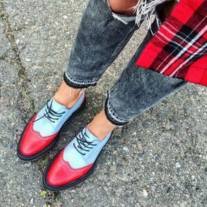 K&ouml;nnte beinhalten: Zweifarbige Oxford-Schuhe mit hellblauem Obermaterial und roten Akzenten an Zehen und Ferse. Schwarze Schn&uuml;rsenkel und Sohle. Die Schuhe werden mit einer Jeans mit Used-Look getragen. Ein modisches Schuhwerk.