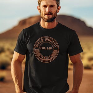 May include: A black short-sleeved t-shirt featuring a circular graphic on the chest. The design includes the text "WALK WORTHY" at the top, "COL. 1:10" in the center, and "ALL4HIM" at the bottom, all rendered in a muted, weathered brown tone.