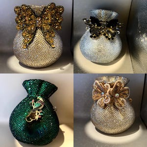 Op de afbeelding: Vier avondtassen bedekt met strass in verschillende kleuren. Eén is zilver met een gouden strik, een andere is zilver met een zwarte strik, een derde is smaragdgroen met een juwelen versiering en de laatste is zilver met een bloemenmotief.