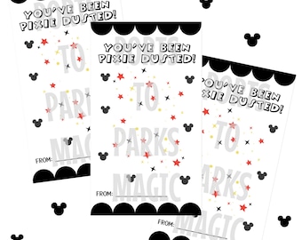 以下が含まれることがあります： 黒いスカラップの縁と「YOU'VE BEEN PIXIE DUSTED！」というテキストが黒で書かれた3枚の白いカード。カードには赤と黄色の星、ミッキーマウスのシルエット、そして「TO PARKS MAGIC」という言葉がグレーで書かれています。各カードには「FROM：」の行があります。