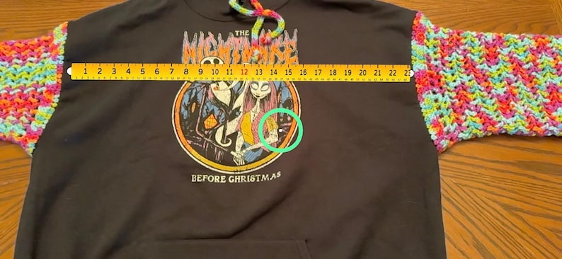 Puede incluir: Sudadera con capucha negra con mangas de ganchillo coloridas. La parte delantera presenta un gr&aacute;fico de "Pesadilla antes de Navidad". Las mangas miden aproximadamente 56 cm de largo. El cord&oacute;n de la capucha es arco&iacute;ris.