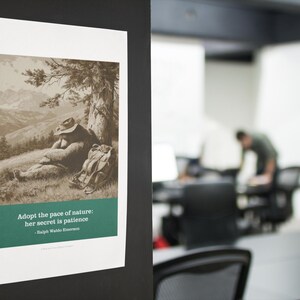 May include: A framed print featuring a sepia-toned illustration of a person resting under a tree in a mountainous landscape. The print includes the quote, "Adopt the pace of nature: her secret is patience" by Ralph Waldo Emerson.