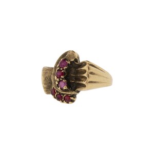 May include: A gold-toned ring featuring a cluster of small, round, red gemstones. The ring has a textured design on the band and around the gemstone setting. The gemstones are set in a dark, textured setting.