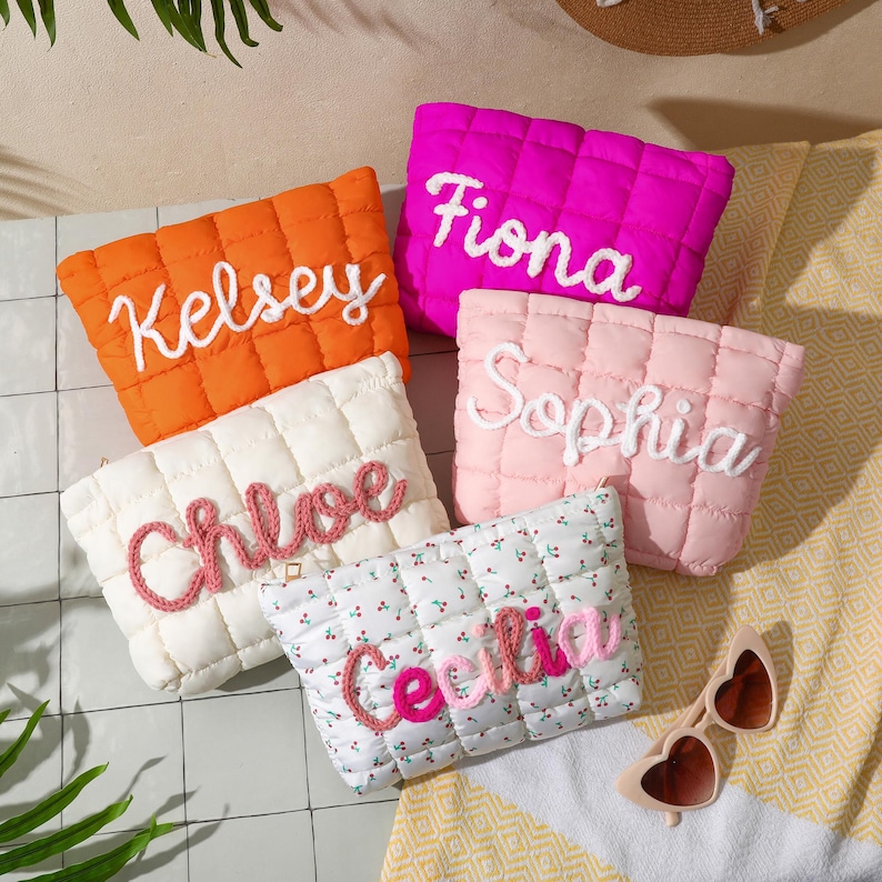 May include: Five quilted pouches in vibrant colours: orange, fuchsia, cream, light pink, and a floral pattern. Each pouch features an embroidered name: Kelsey, Fiona, Chloe, Sophia, and Cecilia. Heart-shaped sunglasses are also visible.