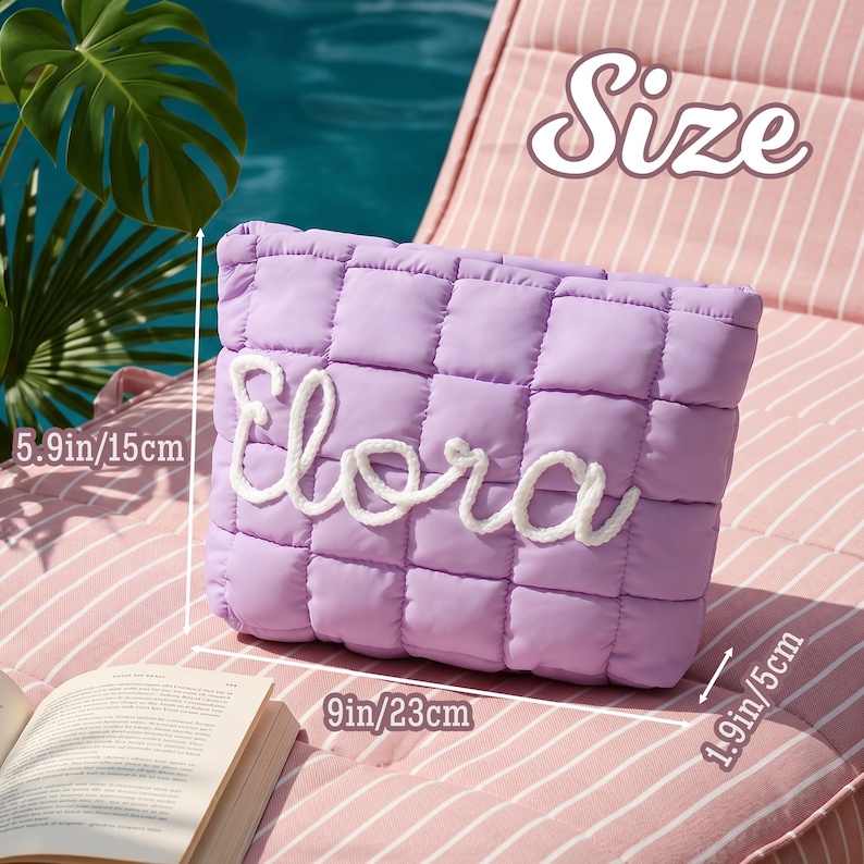 May include: A lavender quilted clutch bag with the name "Elora" embroidered in white. The bag measures 23 cm wide, 15 cm high, and 5 cm deep. The word "Size" is in the upper right corner.