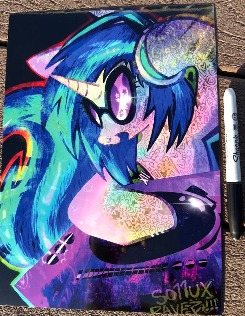 K&ouml;nnte beinhalten: Eine farbenfrohe Illustration eines Ponys mit blauen Haaren, einem Horn und einer Brille. Das Kunstwerk zeigt leuchtende Farbt&ouml;ne von Blau, Lila und Rosa, mit komplizierten Mustern und dem Text "SO11UX RAVEZ!!!". Ein schwarz-wei&szlig;er Sharpie-Marker liegt daneben.