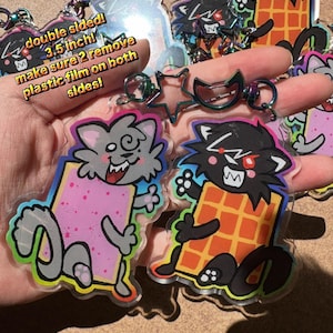 May include: Double-sided acrylic keychains featuring cartoon cat characters holding food items. The keychains are 3.5 inches in size and have a protective plastic film. The text on the image says "double sided! 3.5 inch! make sure 2 remove plastic film on both sides!"