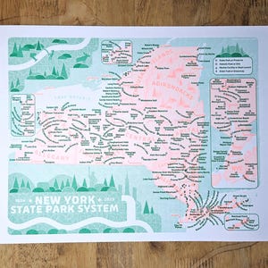 May include: A print of the New York State Park System map, featuring a teal and coral color scheme. The map includes illustrations of trees, mountains, and lakes. The text "1924 New York 2025 State Park System" is printed at the bottom.