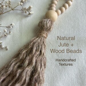 May include: A handcrafted jute tassel with a loop of wooden beads. The tassel is a natural beige color, with the text "Natural Jute + Wood Beads" and "Handcrafted Textures" in the image.