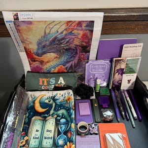 Peut inclure: Un ensemble de papeterie et d'artisanat comprenant un kit de broderie diamant dragon avec le texte DP2009-J, une trousse avec le texte IT'S A GOOD DAY, un livre illustr&eacute; d'un dragon avec le texte Be Stay Kind Weird, des stylos et des notes.