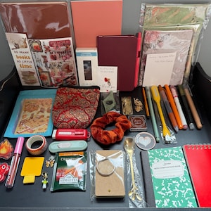 Everything But the Book means that you will receive the accessories you would love to have while Reading, Journaling, Scrapbooking, Note taking and so much more without receiving the actual Book. Picture above shows an example of what a mystery bookish bundle looks like.