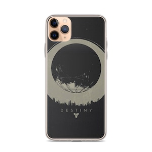 Peut inclure: Une coque de smartphone transparente avec un motif graphique noir et beige représentant un objet sphérique au-dessus d'une silhouette de ville. Le texte DESTINY est imprimé en lettres capitales blanches au-dessus d'une icône géométrique.