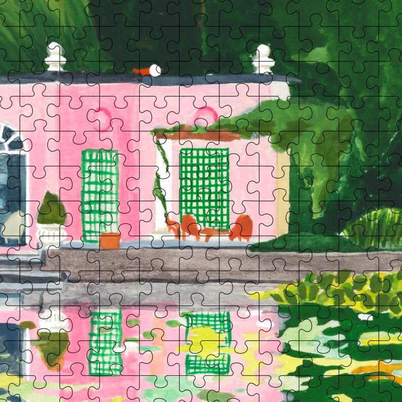 May include: A completed jigsaw puzzle featuring a pink building with green shutters and a black roof. The building has a white trim and is surrounded by green foliage. The puzzle has a watercolor painting style.